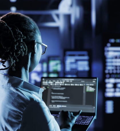 Data center technician runs code Computer scientist running code and programming on laptop, troubleshooting and upgrading high tech facility designed to accommodate multiple clusters of fully operational server rigs